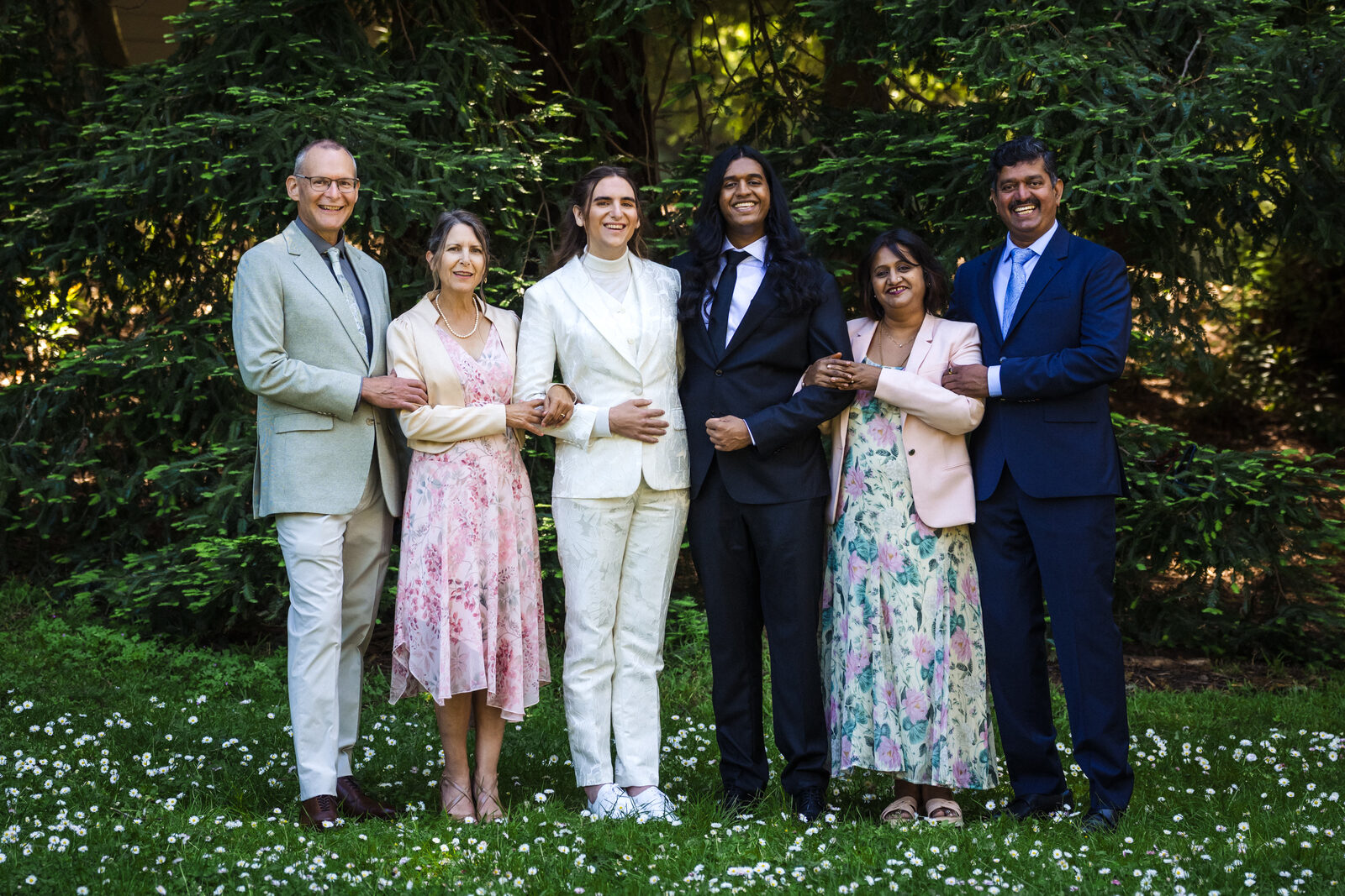 The wedding party arm in arm on the lawn