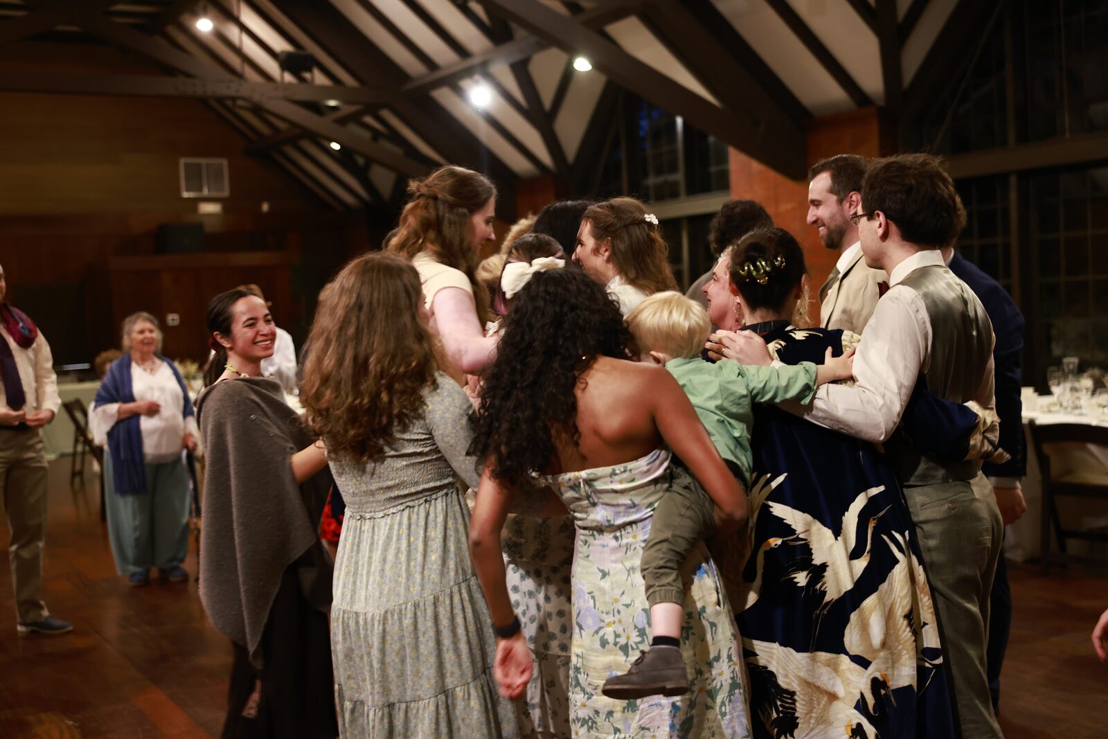 Friends and family in a joyful huddle on the dance floor as evening falls